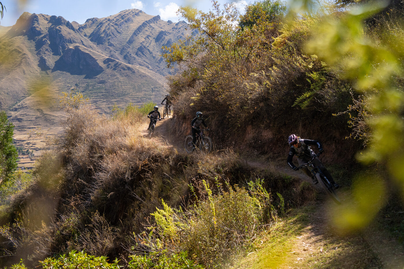 Riders on an exposed ridge with Andean peaks behind