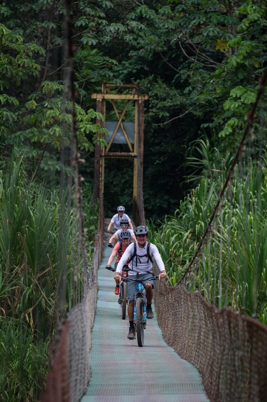 Riders crossing a jungle suspension bridge